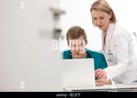 Reifen Arzt diskutieren mit jungen Krankenschwester über Laptop am Schreibtisch im Krankenhaus Stockfoto