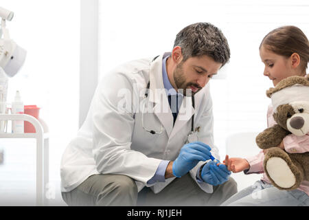 Mitte der erwachsenen Arzt untersuchen Mädchen mit teddybär am Krankenhaus Stockfoto