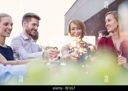 Lächelnd Kollegen Wunderkerzen halten während der Party auf dem Dach Stockfoto