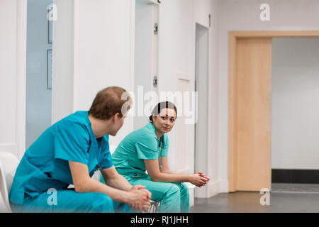 Männliche und weibliche Krankenschwestern Sprechen während der Sitzung in Flur am Krankenhaus Stockfoto