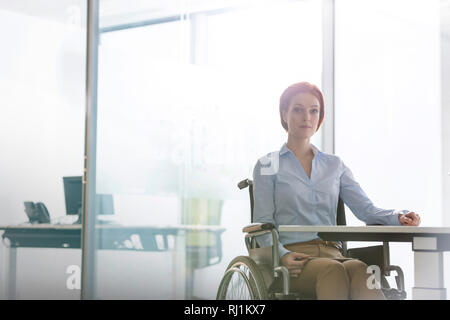 Portrait von zuversichtlich deaktiviert Geschäftsfrau am Schreibtisch im Büro sitzen Stockfoto