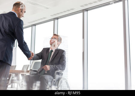 Geschäftsmann Händeschütteln mit lächelnden behinderten Kollegen im Sitzungssaal während der Sitzung im Büro Stockfoto