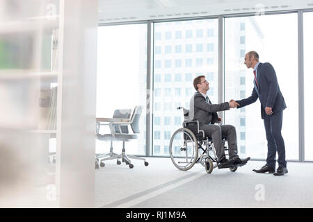 Geschäftsmann Händeschütteln mit lächelnden behinderten Kollegen im Sitzungssaal an Büro Stockfoto