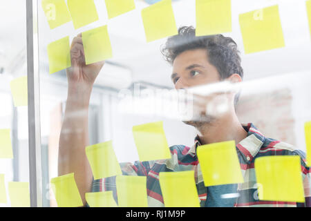Junge Unternehmer schreiben auf Haftnotizen im Büro Stockfoto
