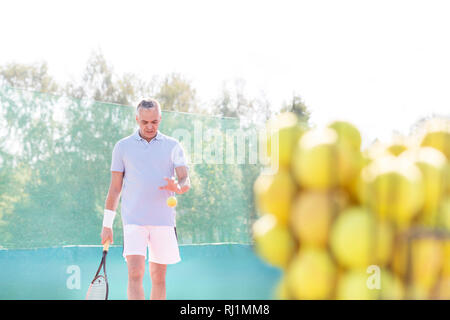 Reifer Mann Tennis spielen gegen den klaren Himmel an einem sonnigen Tag Stockfoto