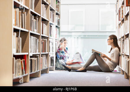 Lächelnd Studenten Buch lesen, während an der Bibliothek sitzen Stockfoto