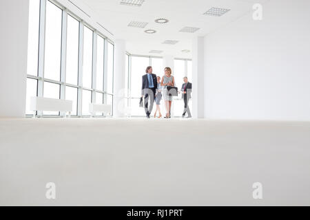 Volle Länge des Kollegen sprechen, während man im Korridor im Büro Stockfoto