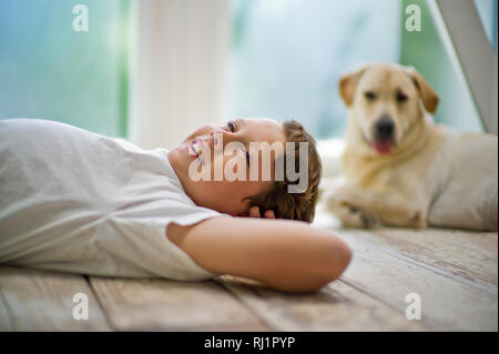 Lächelnd Teenager Träumen, während mit den Händen hinter seinem Kopf lag auf einem Parkettboden. Stockfoto