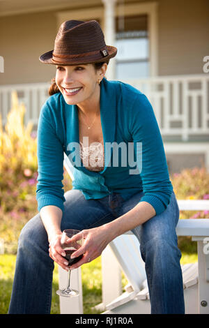 Reife Frau genießt Glas Rotwein in Ihrem Hinterhof. Stockfoto