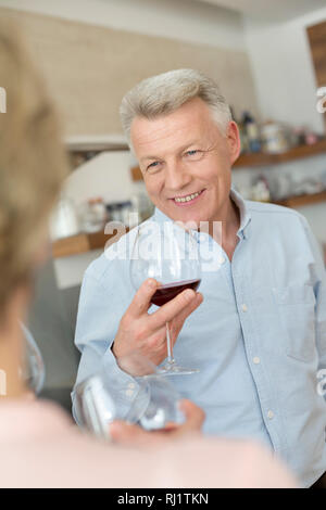 Lächelnd reifer Mann Holding wineglass während Freund suchen Stockfoto