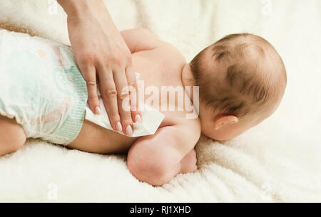 Ein neugeborenes Baby Windel ändern: die Mutter wischt das Baby mit einem Baby abwischen. Das Konzept der Sauberkeit und Pflege Stockfoto