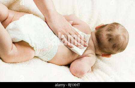 Ein neugeborenes Baby Windel ändern: die Mutter wischt das Baby mit einem Baby abwischen. Das Konzept der Sauberkeit und Pflege Stockfoto