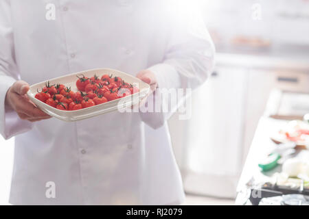 Mittelteil der Küchenchef mit frischen Tomaten in Fach im Restaurant Stockfoto