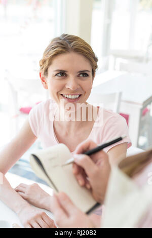 Lächelnde junge Frau Kellnerin schreiben um auf Notepad bei Restaurant suchen Stockfoto