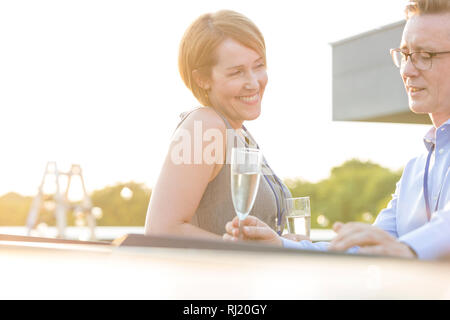 Lächelnd ausgereifte Kollegen sprechen auf der Dachterrasse während Erfolg Partei Stockfoto