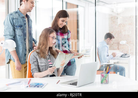 Kollegen mit Fotos und Laptop im Büro Stockfoto