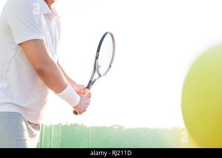 Mittelteil der reifer Mann schlagen Tennis Ball gegen den klaren Himmel Stockfoto