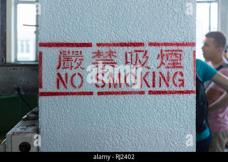 No Smoking Sign stenciled auf weißen Säule am Star Ferry Pier in Tsim Sha Tsui, Hong Kong Stockfoto