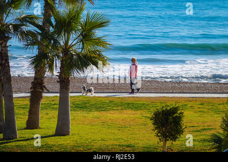 Dog Walker auf die Promenade und das Meer mit Wellen in Oropesa del Mar Resort, Costa del Azahar, Provinz Castellon, Spanien, Oropesa Stockfoto