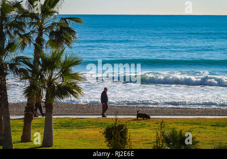 Dog Walker auf die Promenade und das Meer mit Wellen in Oropesa del Mar Resort, Costa del Azahar, Provinz Castellon, Spanien, Oropesa Stockfoto