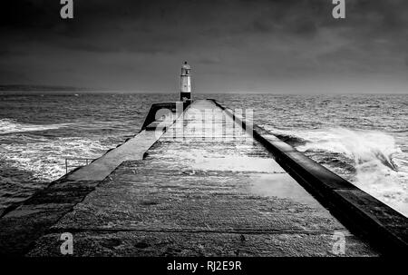 Weg zum Leuchtturm durch den Absturz umgeben, stürmische Wellen in dramatischen Schwarz und Weiß Stockfoto