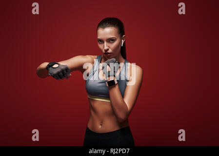 Junge hübsche Sportlerin workout Handschuhe zu tragen bereit ist, einen Gegner zu kämpfen. Über den roten Hintergrund isoliert Stockfoto