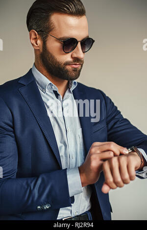 Zeit ist Geld... voll gut aussehender Geschäftsmann im eleganten Anzug und Sonnenbrille ist Kontrolle Zeit beim Warten auf die Partner. Business Look. Mode portrait. Stockfoto