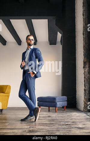 Erfolgreicher Geschäftsmann. Volle Höhe Blick auf attraktive bärtigen Geschäftsmann im eleganten Anzug im modernen Büro. Business Style. Mode suchen. Stockfoto