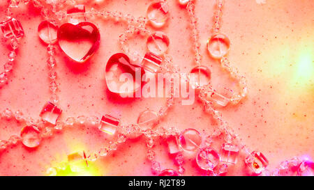 Transparente Herzen und Perlen auf Marmor in rosa Ton. Perfekte Valentinstag Grußkarte Hintergrund. Stockfoto