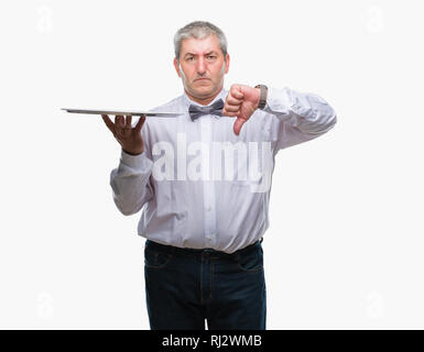 Gut aussehender älterer Kellner Mann hält Silbertablett über isolierte Hintergrund mit Verärgerten Gesicht, negatives Vorzeichen zeigen Abneigung mit Daumen nach unten, Ablehnung con Stockfoto