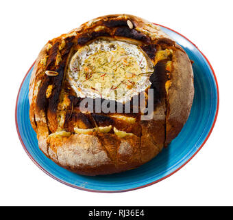 Köstliche französische Fondue aus Camembert Käse geschmolzen in Brot Schüssel mit Pinienkernen und Gewürzen. Auf weissem Hintergrund Stockfoto