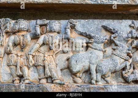 Halebidu, Karnataka, Indien - November 2, 2013: Hoysaleswara Tempel von Shiva. Nahaufnahme von Mädchen und Stiere Skulptur wie ein Band entlang der Wand des Heiligtums. Stockfoto