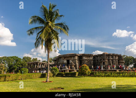 Halebidu, Karnataka, Indien - November 2, 2013: braun Stein flachbild Hoysaleswara Tempel von Shiva in seiner grünen Garten mit Palmen und viel Anhänger Stockfoto