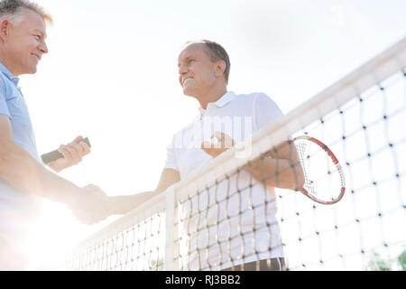 Low Angle View von lächelnden Menschen die Hände schütteln und Tennisplatz gegen den klaren Himmel stehen Stockfoto