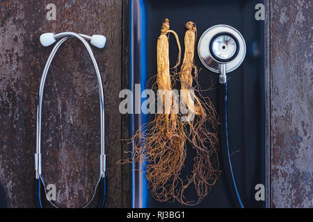 Trockene Ginseng auf schwarze Platte mit Stethoskop auf dem Holz Hintergrund Stockfoto