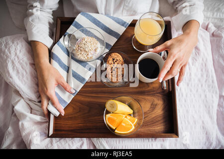 Ein Mittelteil der Frau mit Frühstück im Bett am Morgen. Eine Ansicht von oben. Stockfoto