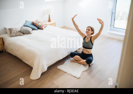Eine junge Frau, Übung im Innenraum in einem Schlafzimmer. Kopieren Sie Platz. Stockfoto