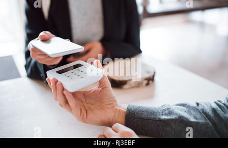 Ein Mittelteil von Kunde und Verkäufer, mobile Zahlung in einem Shop. Stockfoto