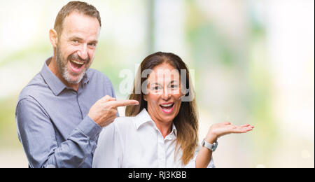 Mittleres Alter hispanic Paar über isolierte Hintergrund erstaunt und lächelt in die Kamera während der Präsentation mit Hand und zeigte mit dem Finger. Stockfoto