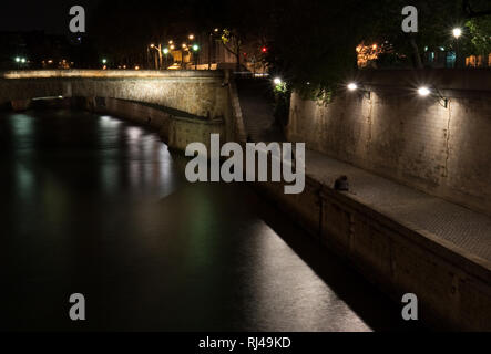 Gruppen von Menschen versammeln sich entlang der Ufer der Seine auf einem Frühling Nacht in Paris. Stockfoto