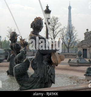 Wasser spritzt aus einer Meerjungfrau Brunnen auf dem Place de la Concorde, den Eiffelturm im Hintergrund auftaucht. Stockfoto