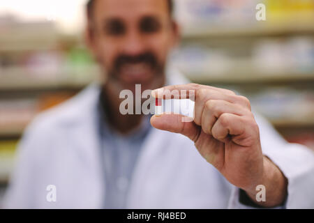 Männliche Apotheker Holding eine Pille. Nahaufnahme einer Hand, die eine Medizin Kapsel. Gesundheitsversorgung und Prävention. Stockfoto