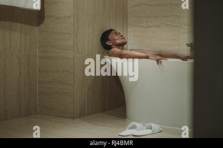 Reifen afrikanische Frau in der Badewanne liegen, mit geschlossenen Augen. Weibliche Entspannung in der Badewanne. Stockfoto
