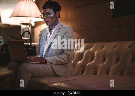 Geschäftsfrau im Hotel Lobby sitzen und Arbeiten am Laptop. Afrikanische Frauen CEO auf Geschäft Tour mit Laptop in der Lobby des Hotels. Stockfoto