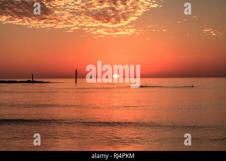 Schwimmen bei Sonnenuntergang mit einem roten Himmel über Süden Marco Island Beach in Florida Stockfoto