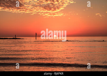 Schwimmen bei Sonnenuntergang mit einem roten Himmel über Süden Marco Island Beach in Florida Stockfoto