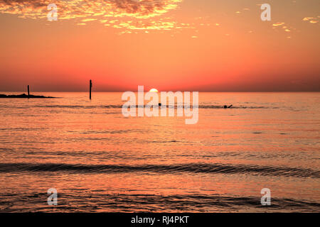 Schwimmen bei Sonnenuntergang mit einem roten Himmel über Süden Marco Island Beach in Florida Stockfoto