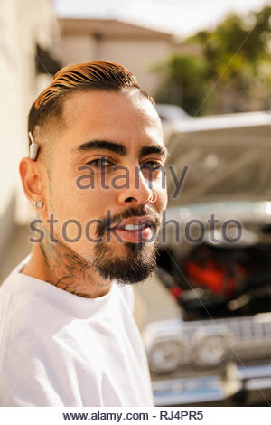 Portrait zuversichtlich, coole Latinx junger Mann mit Tattoos und Marihuana gemeinsame hinter dem Ohr