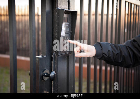 Finger picking Nummer auf speakphone in verschlossenen Metal Gate Eingang zu Hause in Warschau, Polen, Stockfoto