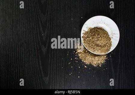 Künstlerische Fotografie der yerba mate Infusion, typische aus Argentinien, in eine weiße Platte, über einen dunklen Hintergrund Stockfoto